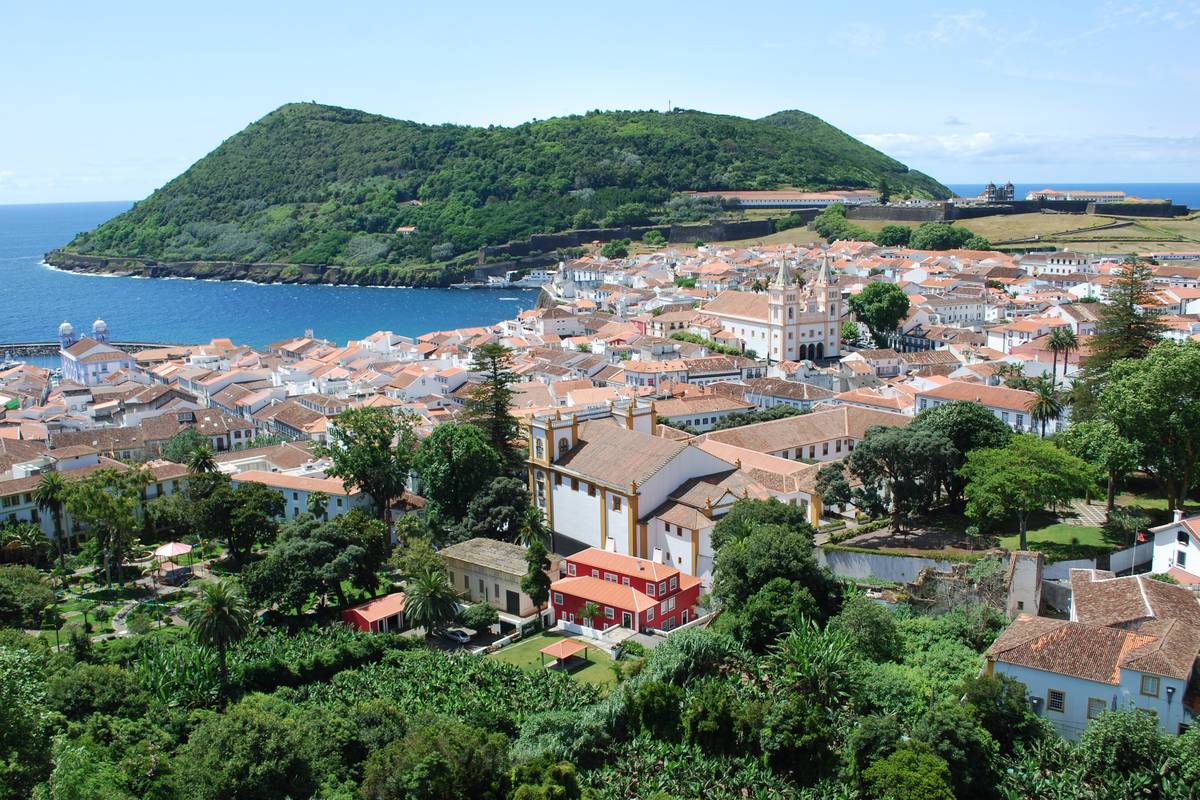Utsikt över Angra do Heroísmo på Terceira med röda tegeltak, katedralen, gröna trädgårdar och vulkanhalvön Monte Brasil vid havet