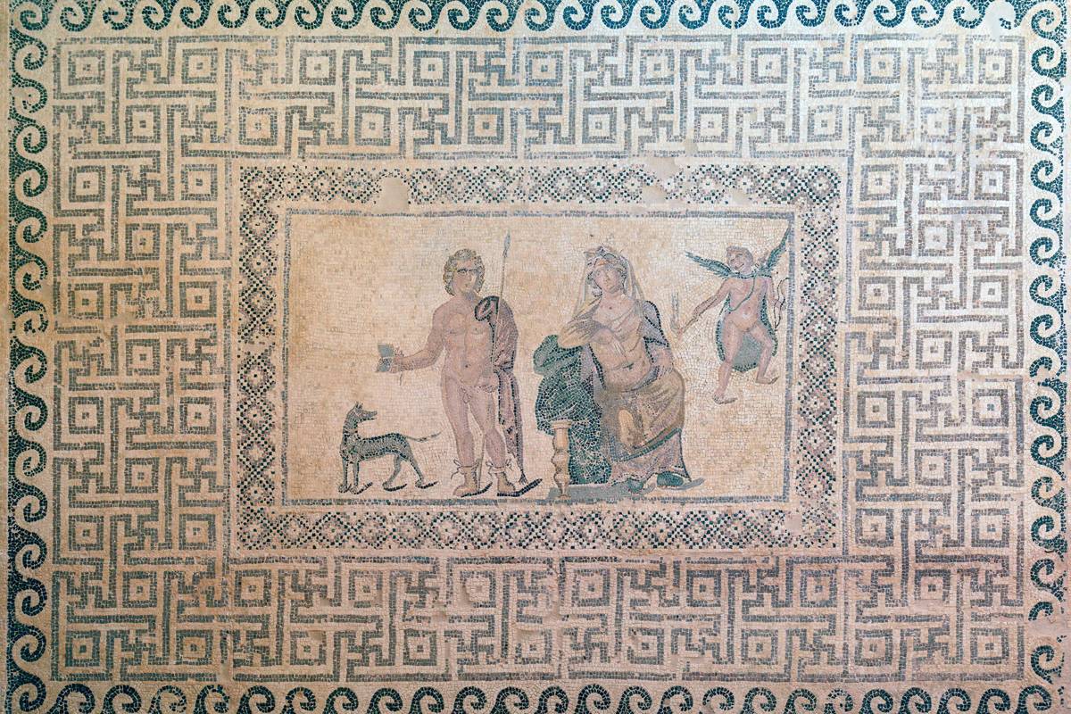 Romerskt mosaikgolv i Dionysos hus i Pafos, med en bildruta av mytologiska gestalter omgiven av ett tätt geometriskt mönster i rött, svart och vitt