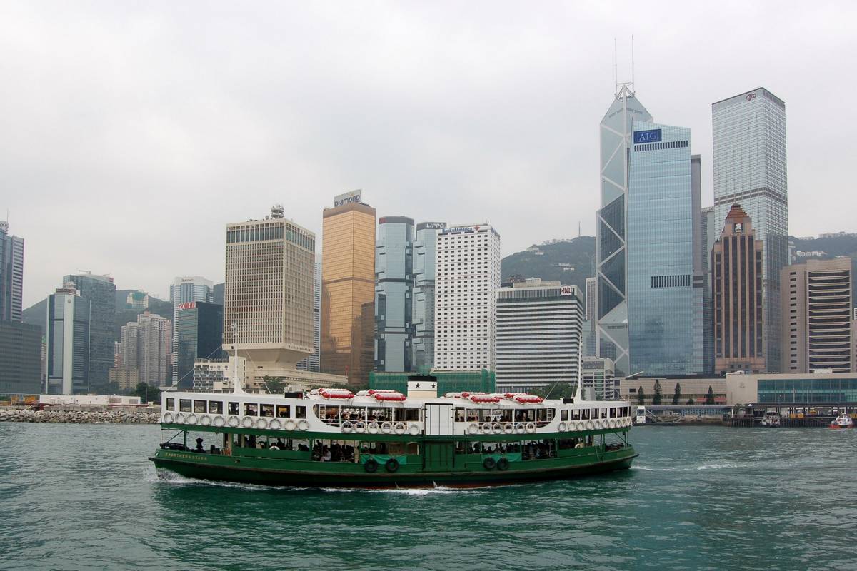 Grön-vit Star Ferry-båt på Victoria Harbour framför skyskrapor på Hongkongön