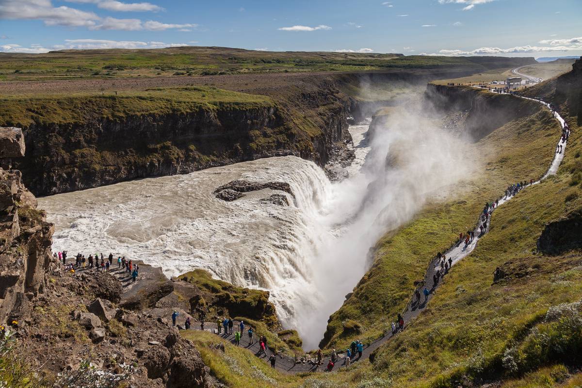 Vattenfallet Gullfoss som störtar ner i en djup ravin med vit vattendimma och gröna sluttningar på båda sidor
