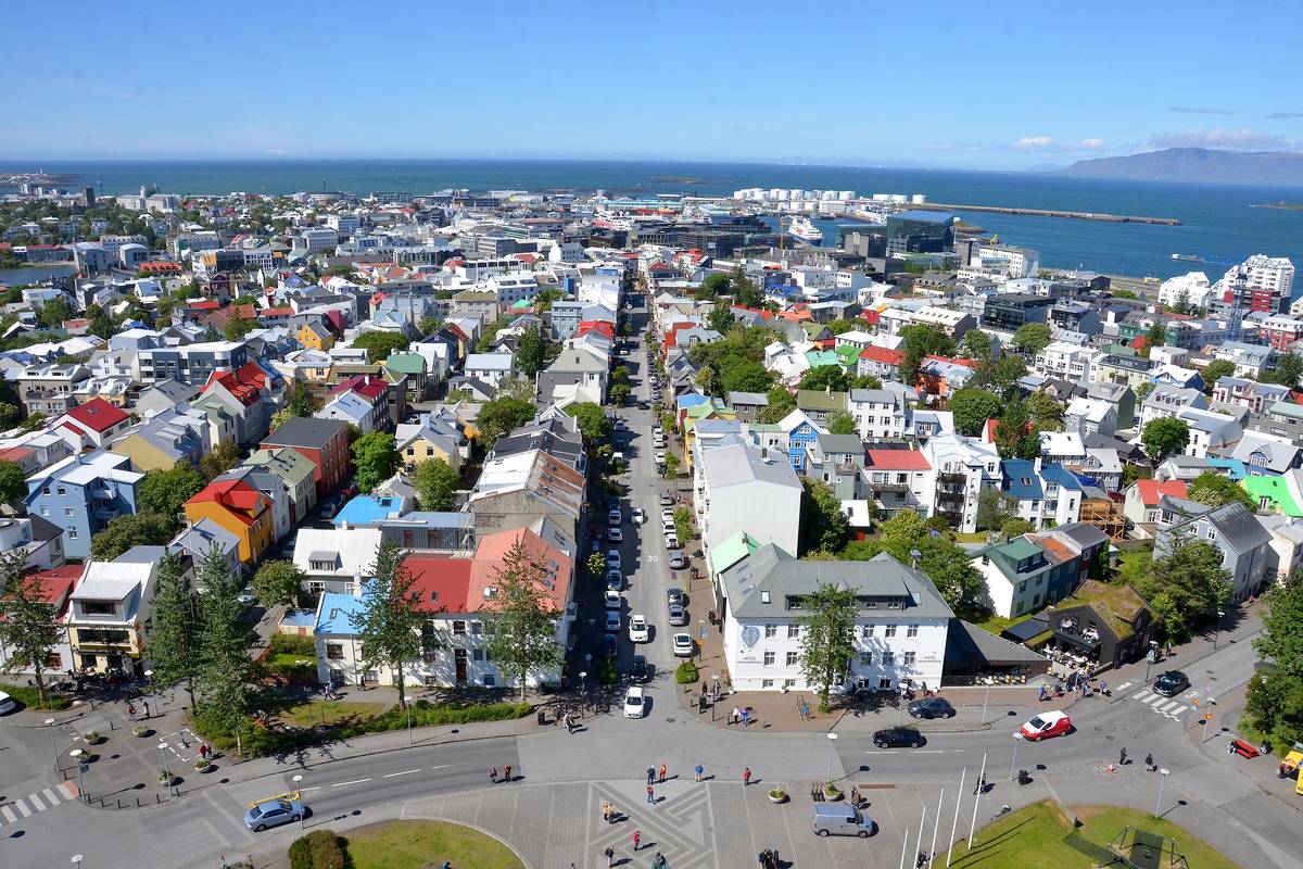 Utsikt från tornet på Hallgrímskirkja över Reykjavíks färgglada hustak, med havet och bergen i bakgrunden