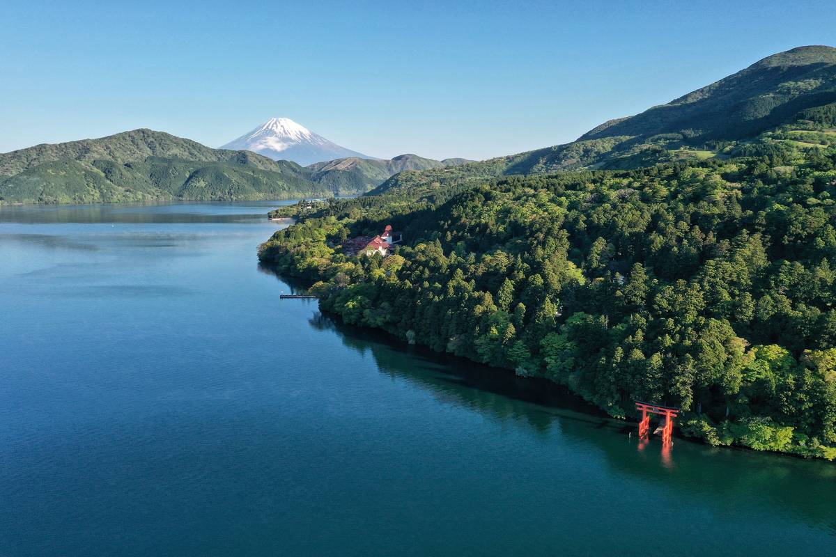 Den röda toriiporten vid Hakonehelgedomen står i sjön Ashi med det snötäckta berget Fuji i bakgrunden