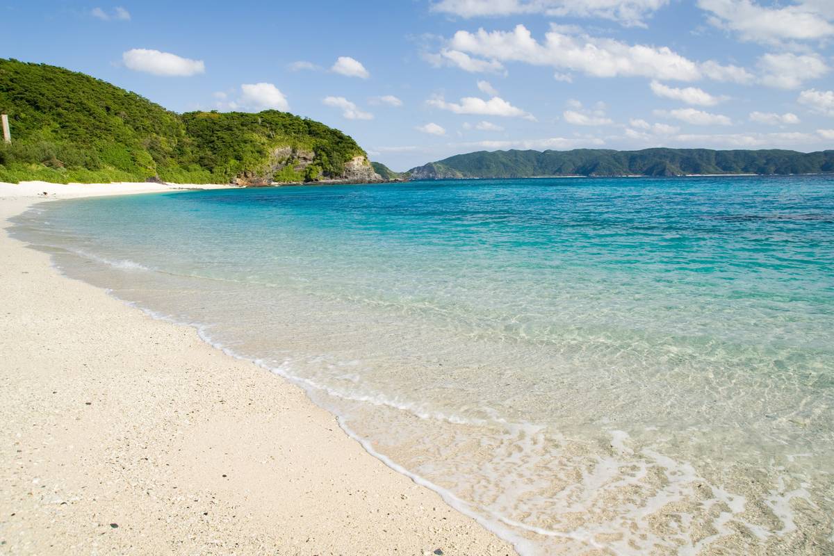 Turkost, klart vatten och vit sand på stranden Furuzamami på ön Zamami i Okinawa