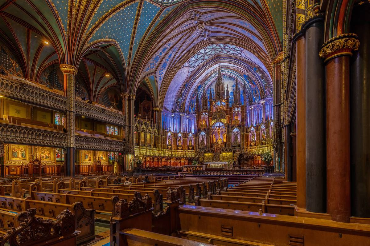 Interiören i basilikan Notre-Dame i Montréal med djupblå valv, gyllene detaljer och träbänkar fram mot det upplysta altaret