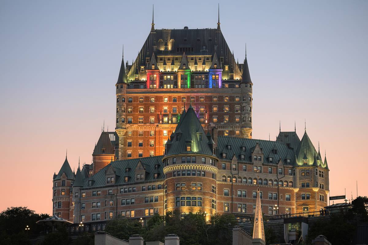 Château Frontenac med sina gröna koppartak och tegelfasad upplyst i skymningen under en rosa och blå himmel i Québec City