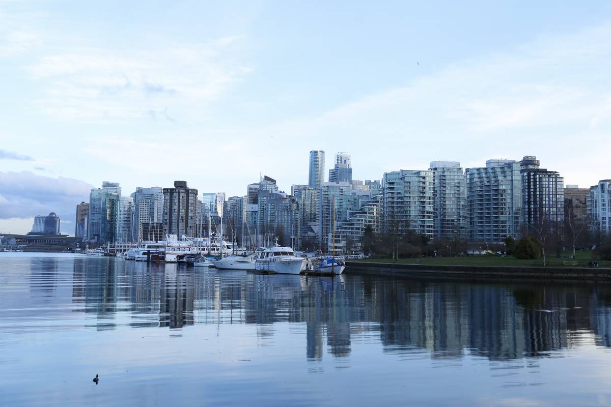 Vancouvers glänsande skyskrapor och en småbåtshamn speglar sig i det stilla vattnet, sett från Stanley Park i kvällsljus