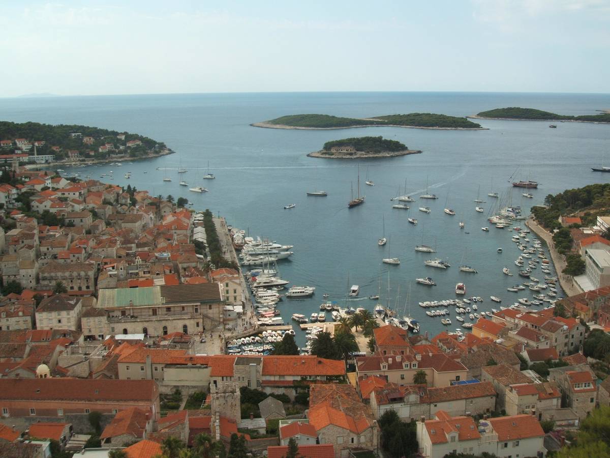Utsikt från fästningen över staden Hvar med röda tak, en hamn full av segelbåtar och de gröna Pakleniöarna ute i havet
