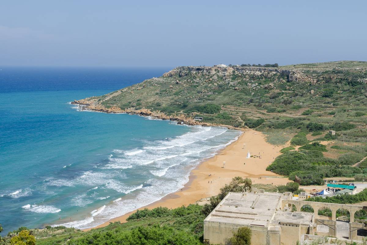 Ramla Bay på Gozo med en lång strand av rödgyllene sand, vita vågor och gröna sluttningar som slutar i en udde ut mot det blå havet