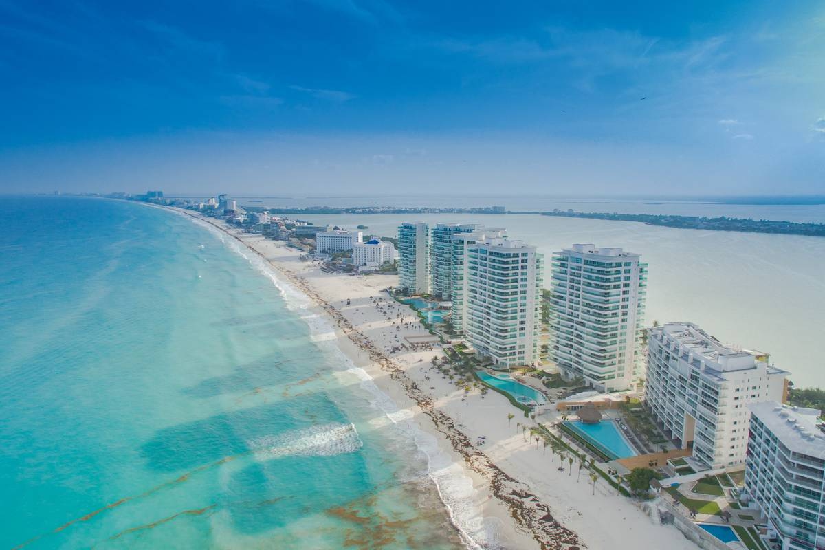 Flygbild över Cancúns hotellzon med höga hotell på en smal remsa mellan turkost hav och en lagun