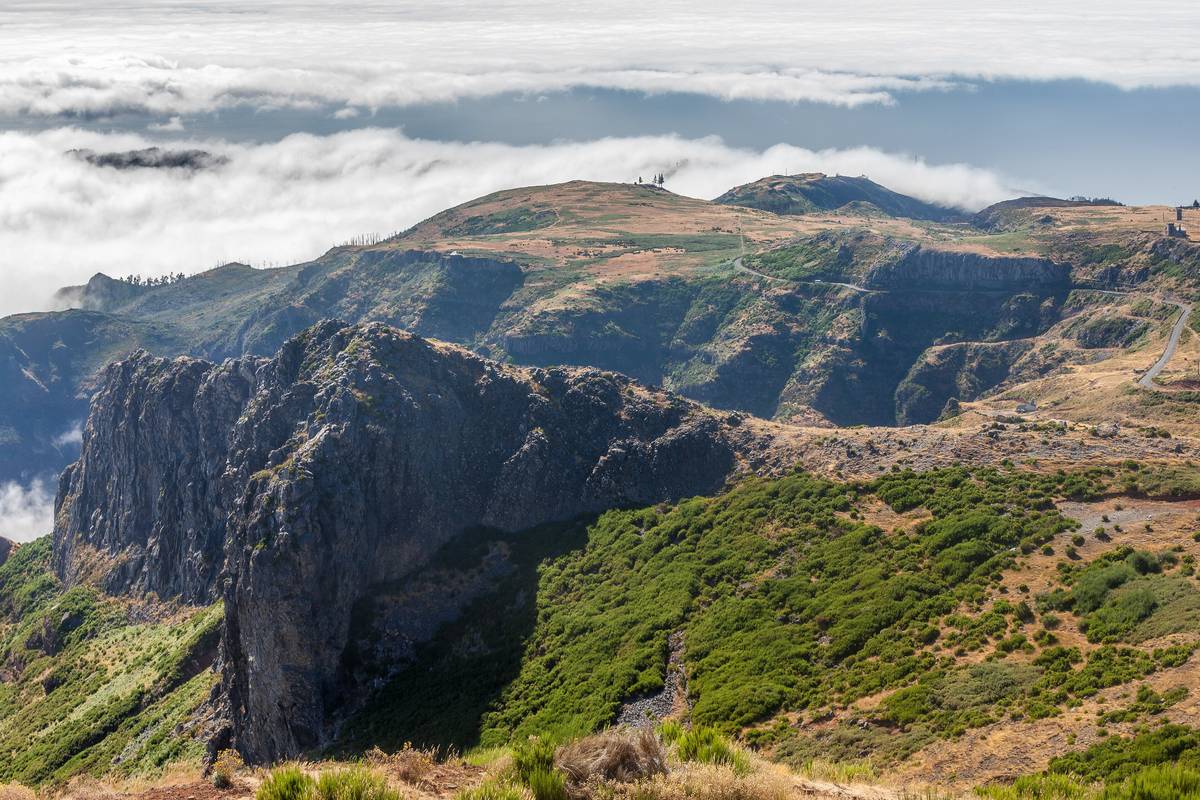Utsikt från Pico do Arieiro på Madeira över branta bergskammar med grön vegetation och ett molnhav under topparna