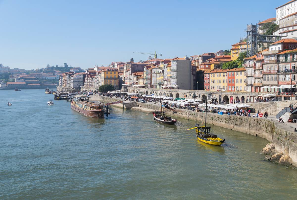 Kajen Ribeira i Porto sedd från bron Luiz I, med färgglada smala hus längs floden Douro och traditionella träbåtar vid stranden