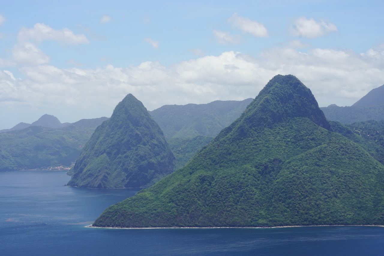 De två skogsklädda vulkantopparna Petit Piton och Gros Piton som reser sig ur det blå havet på St Lucias sydvästkust, sedda från luften