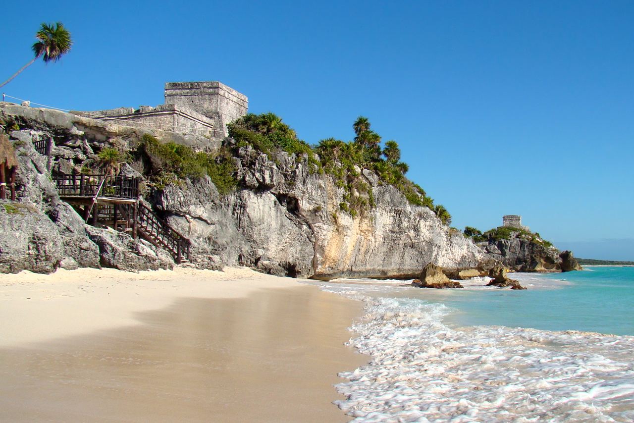 Mayaruinen El Castillo på en kalkstensklippa ovanför en vit sandstrand och turkost vatten i Tulum
