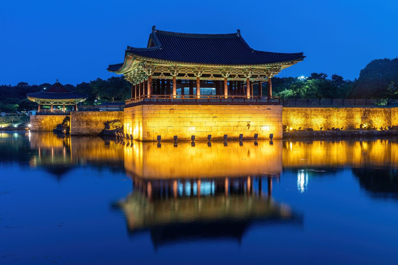 Den upplysta paviljongen i Donggung-palatset speglar sig i den stilla dammen Wolji i Gyeongju under den blå timmen efter solnedgången
