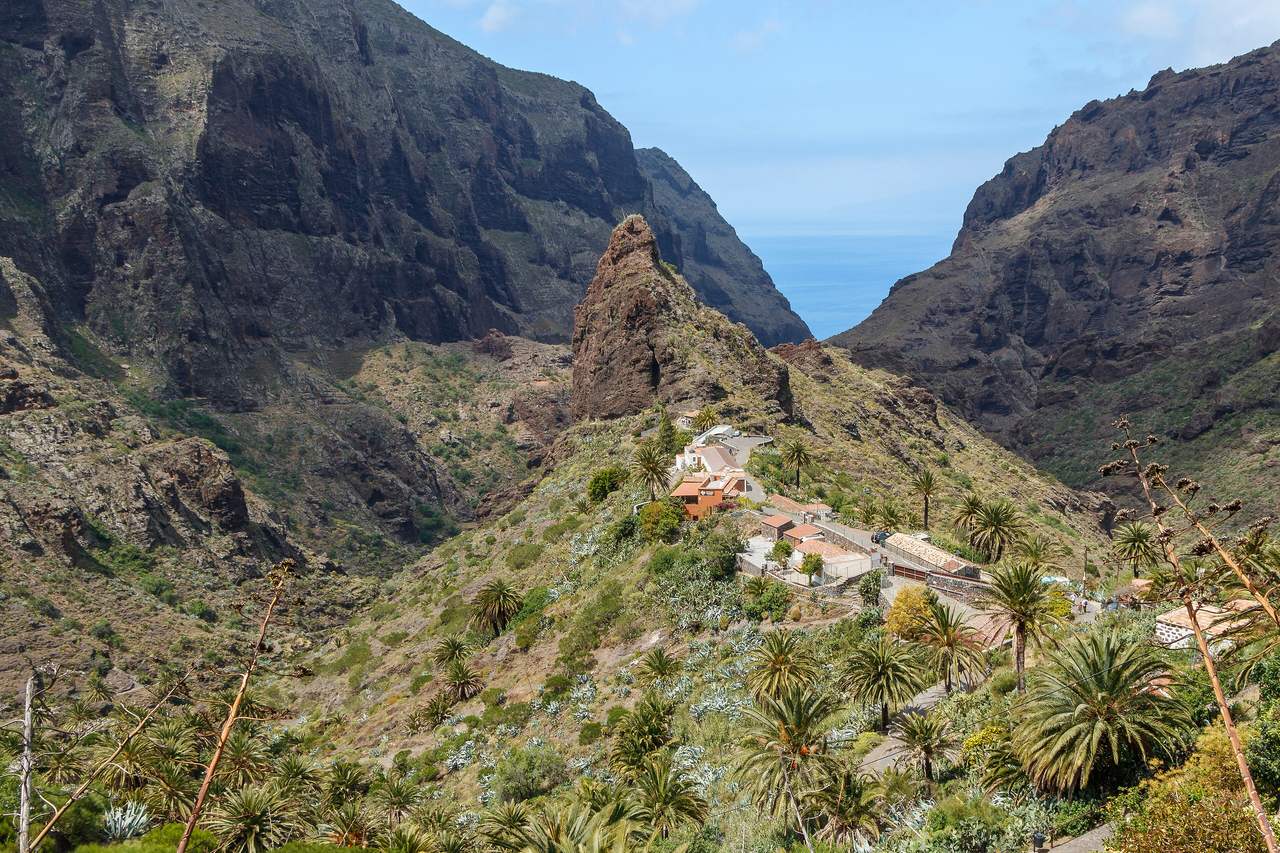 Bergsbyn Masca på Teneriffa på en grön ås med palmer, omgiven av branta klippor i Tenomassivet och en skymt av havet längst bort